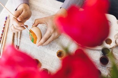 Mutlu Paskalya kavramı. Holding ve boya, fırça, lale buketi, metin için yer ile rustik tablo easter egg boyama eller. Paskalya yumurtası, tatil hazırlıkları dekorasyon.