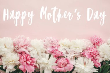 Mutlu anneler günü metni imzalamak peonies düz yatıyordu. Pembe ve beyaz peonies pastel pembe kağıt üzerinde kenarlık 