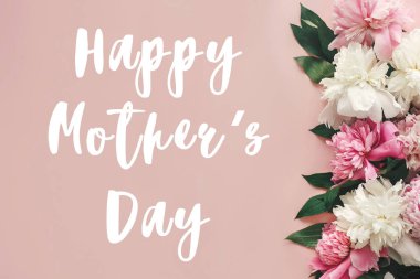 Mutlu anneler günü metni imzalamak peonies düz yatıyordu. Pembe ve beyaz peonies pastel pembe kağıt üzerinde kenarlık