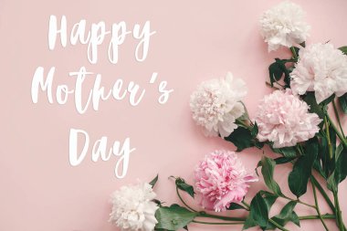 Mutlu anneler günü metni imzalamak peonies düz yatıyordu. Pembe ve beyaz peonies pastel pembe kağıt üzerinde kenarlık