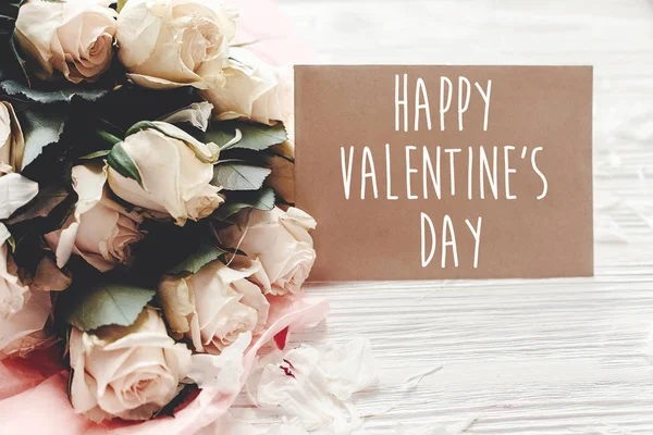 幸せなバレンタインデーのテキスト署名クラフト グリーティング カードと木製の背景の白いバラのブーケ — ストック写真