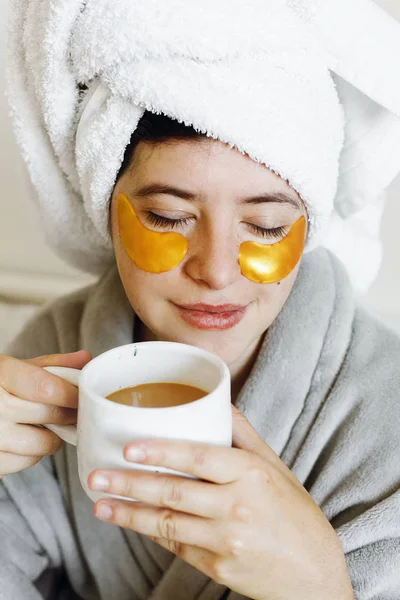 Beautiful Young Woman Golden Eye Patches Bathrobe Holding Cup Coffee — Stock Photo, Image