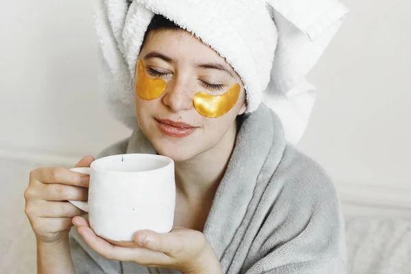 Beautiful Young Woman Golden Eye Patches Bathrobe Holding Cup Coffee — Stock Photo, Image