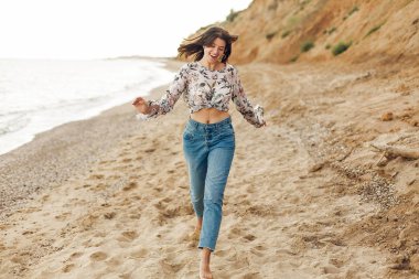 Çalışan ve rock ile güneşli plajda eğlenerek mutlu genç boho kadın. Rahatlatıcı ve denizde gülümseyen hipster ince kız. Yaz tatil kavramı. Uzay kopyalayın. Neşeli an