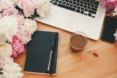 Şık dizüstü, kahve Kupası, defter, kalem, pembe ve beyaz peoni