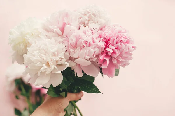 Hand met stijlvolle roze en witte pioenrozen boeket op roze pape — Stockfoto