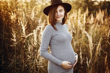 Belly ve SÜ rahatlatıcı ellerinde tutan şık hamile kadın