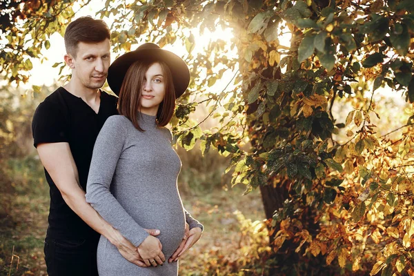 Güneşli ışıkta karnından üzerinde şık hamile çift ellerimi — Stok fotoğraf