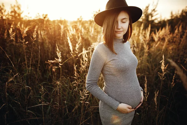 Élégante femme enceinte tenant la main sur le ventre et se détendre dans su — Photo