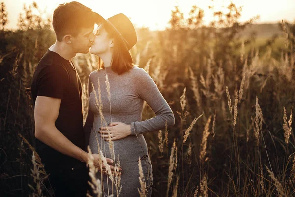 Elegante pareja embarazada cogida de la mano en el vientre y besándose en su —  Fotos de Stock