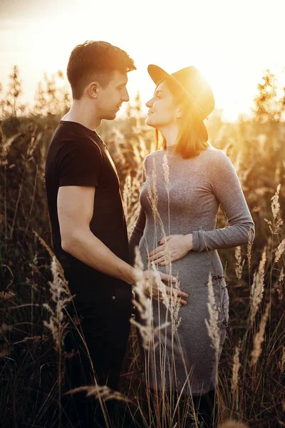 Elegante casal grávida de mãos dadas na barriga na luz do sol em — Fotografia de Stock