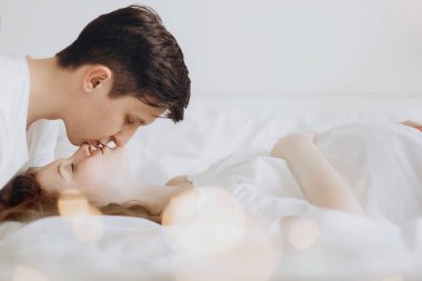 Beyaz yatakta mutlu hamile çift rahatlatıcı ve göbek bu holding