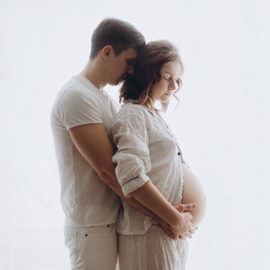 Onun hamile eşi sarılma ve göbek tutan genç koca mutlu 