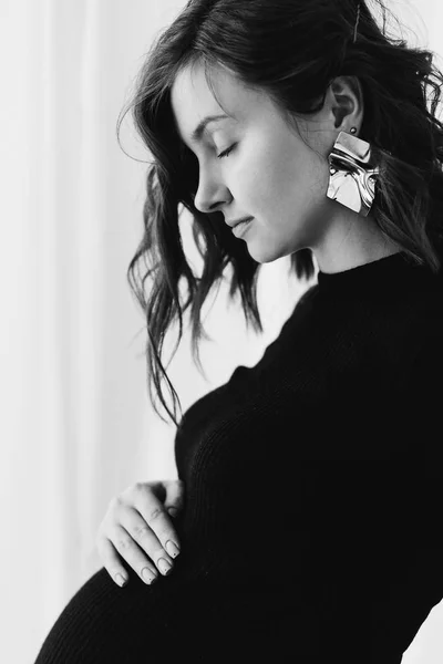 Jovem mulher grávida feliz em vestido preto elegante e ouvido moderno — Fotografia de Stock