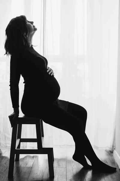 앉아서 하는 세련 된 검은 드레스에 행복 한 임신 여자의 실루엣 — 스톡 사진