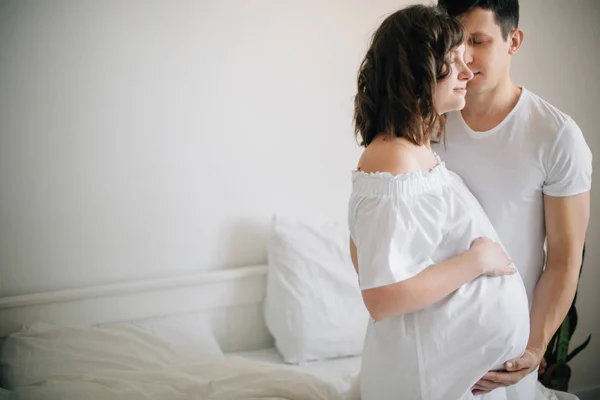 Feliz joven marido besando a su sonriente esposa embarazada y abrazo — Foto de Stock