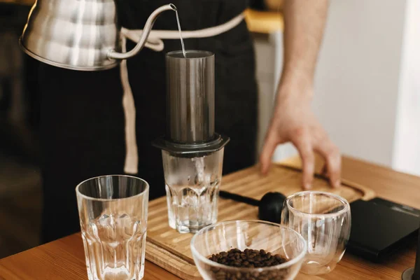 Profissional barista em preto avental elegante derramando água quente em — Fotografia de Stock