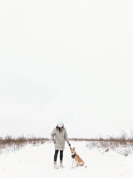 Стильная хипстерша гуляет с милой золотой собакой на снежном холоде. — стоковое фото
