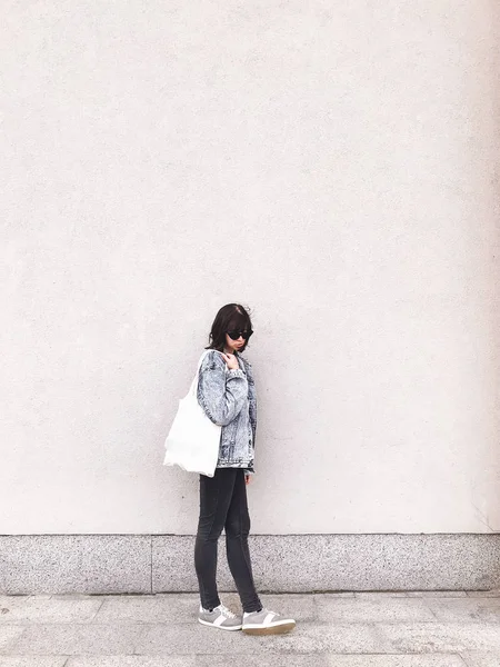Stijlvolle hipster meisje in denim outfit en tote tas poseren in de stad — Stockfoto