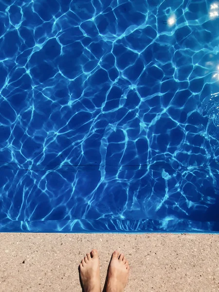 Lány cserzett lábát állandó kék víz medence napos fény — Stock Fotó