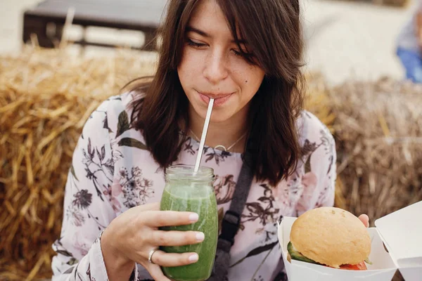 Elegante chica hipster sosteniendo deliciosa hamburguesa vegana y beber —  Fotos de Stock