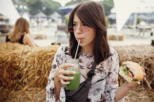 Menina elegante hipster segurando delicioso hambúrguer vegan e beber — Fotografia de Stock