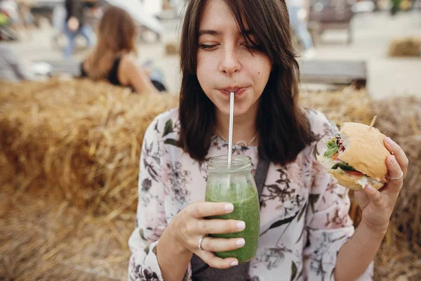 Elegante chica hipster sosteniendo deliciosa hamburguesa vegana y beber —  Fotos de Stock