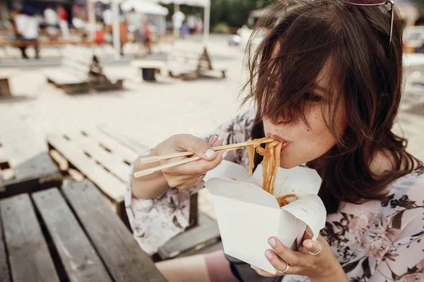 Stylish hipster girl eating wok noodles with vegetables and seaf — Stock Photo, Image