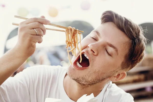 Elegante hombre hambriento comiendo deliciosos fideos wok con verduras — Foto de Stock