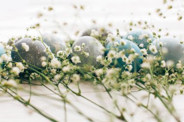 Beyaz ahşap backgrou bahar çiçekleri ile şık Paskalya yumurtaları