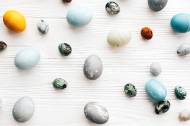 Şık Paskalya yumurtaları düz beyaz ahşap zemin üzerinde yatıyordu. Modern 