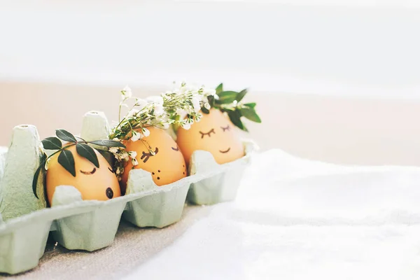 Стильные пасхальные яйца с милыми лицами в цветочных венках — стоковое фото