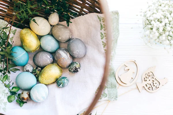 Стильные пасхальные яйца и зеленые ветви баксус в плетеной корзине на — стоковое фото