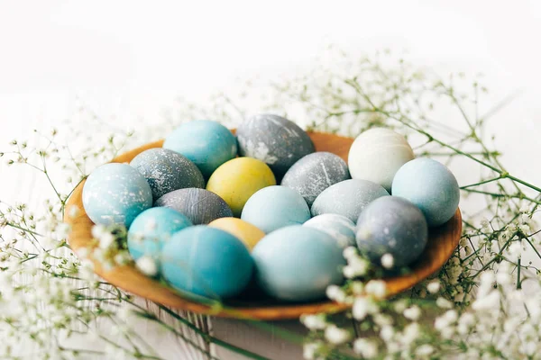 Stylish Easter eggs with spring flowers in wooden plate on white — Stock Photo, Image
