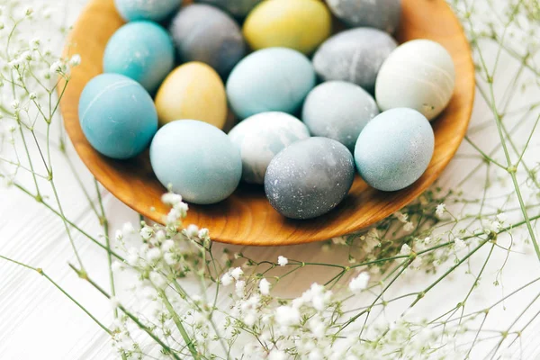 Stylish Easter eggs with spring flowers in wooden plate on white — Stock Photo, Image