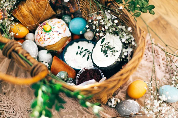 Stylish Easter basket with modern eggs, easter bread cake, ham,