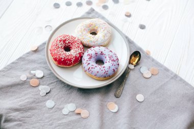 WHI üzerinde şık plaka üzerinde sprinkles ile lezzetli renkli donut