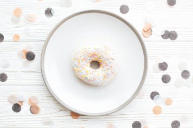 Whit üzerinde şık plaka üzerinde renkli sprinkles ile lezzetli çörek