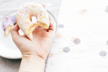 Donut renkli sprinkles ile lezzetli lokma tutan el