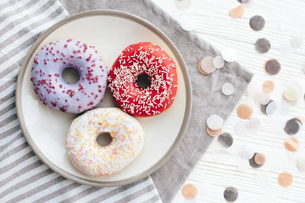 WHI üzerinde şık plaka üzerinde sprinkles ile lezzetli renkli donut