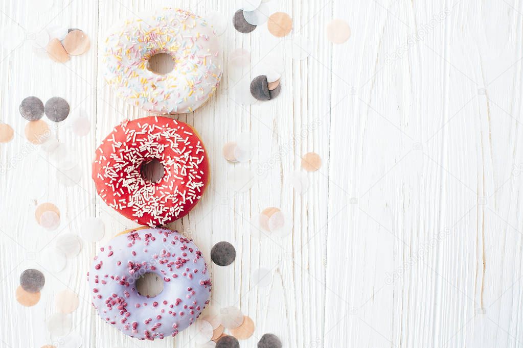 Delicious colorful donuts with sprinkles on stylish  white table