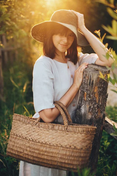 Stylish girl in linen dress holding rustic straw basket at woode — Stock Photo, Image