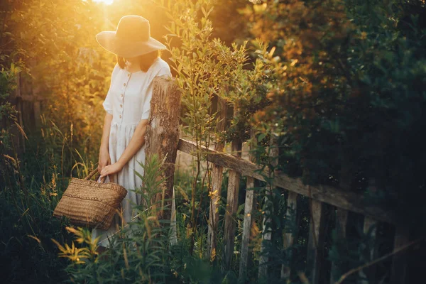 Stijlvolle meisje in linnen jurk rustieke stro mand op woode houden — Stockfoto