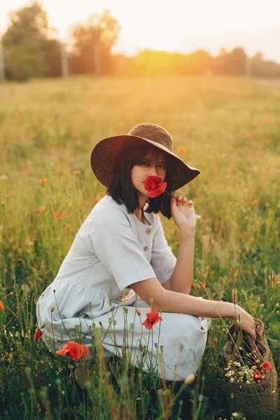 Elegante chica en vestido de lino sosteniendo flor de amapola en el prado en su — Foto de Stock