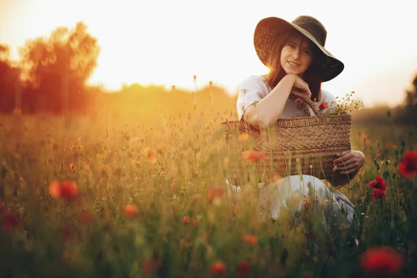 Stylish girl in linen dress smiling in poppy meadow in sunset li — Stock Photo, Image