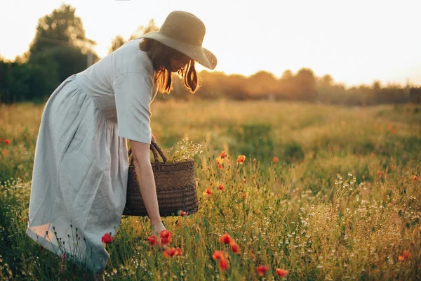 Стильна дівчина в лляній сукні, що збирає квіти в сільській соломі ба — стокове фото