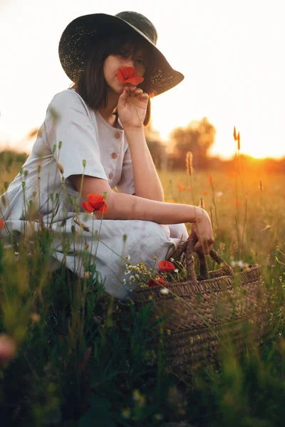 Stijlvolle meisje in linnen jurk bedrijf poppy bloem in weide in su — Stockfoto