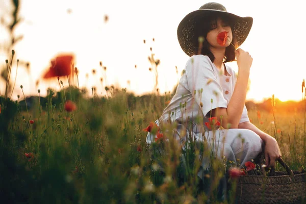 Стильна дівчина в лляній сукні пахне маковою квіткою на лузі в с — стокове фото