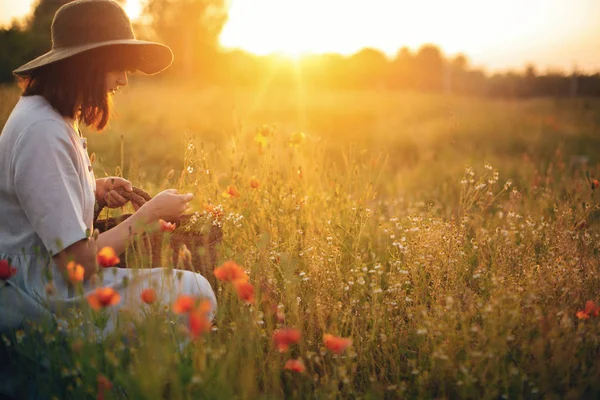 Stijlvolle meisje in linnen jurk verzamelen van bloemen in rustieke stro ba — Stockfoto