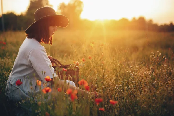 Стильна дівчина в лляній сукні, що збирає квіти в сільській соломі ба — стокове фото